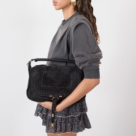 Model carrying Chloe Marcie Small Shoulder Bag in black calfskin with gold-tone hardware and stud detailing, styled with grey hoodie and floral mini