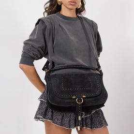 Model carrying Chloe Marcie Small Shoulder Bag in black calfskin with stud detailing and gold-tone hardware, styled with grey tee and floral mini
