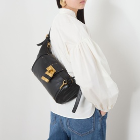 Model carrying Chloe Paddington Hobo Shoulder Bag in black leather with gold-tone padlock and hardware, worn crossbody over white blouse with jeans
