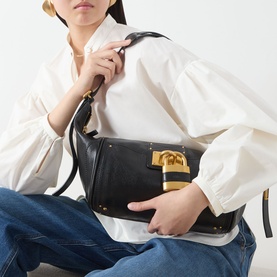 Model carrying Chloe Paddington Hobo Shoulder Bag in black leather with gold-tone padlock hardware, styled with white blouse and jeans