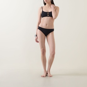 Model wearing Eres Clap Cut-Out Classic Bikini Briefs in Noir, styled with matching black bralette top with cut-out hardware detail.