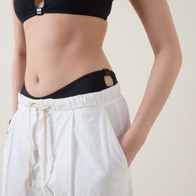 Model wearing Eres Clap Cut-Out Classic Bikini Briefs in Noir with cut-out detail, styled with white wide-leg trousers