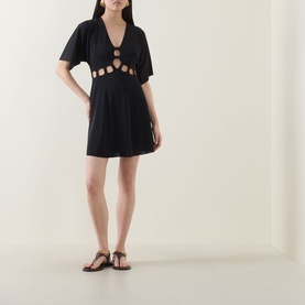 Model wearing Eres Connection Cut-Out Beach Dress in Noir with V-neckline, flutter sleeves, gold ring cut-out detail and flared mini skirt, styled