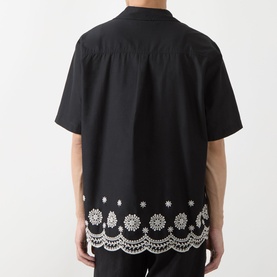 Model wearing Les Deux Border Embroidered Shirt in tap shoe black, rear view showing white floral embroidered scalloped hem and short sleeves.