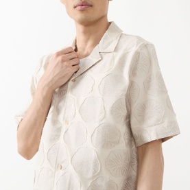 Model wearing Les Deux Dahlia Jacquard Shirt in light sand, camp collar, short sleeves, floral medallion jacquard pattern, adjusting collar