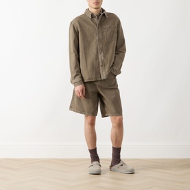 Model wearing Les Deux Chest Pocket Denim Overshirt in light brown denim wash, styled with matching shorts and grey loafers.