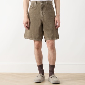 Model wearing Les Deux Washed Denim Shorts in light brown denim wash, five-pocket style, styled with grey socks and sandals.