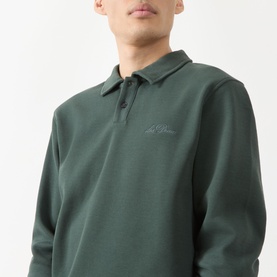 Model wearing Les Deux Script Logo Polo Sweater in pine green with flat collar, button fastening, and embroidered script logo detail