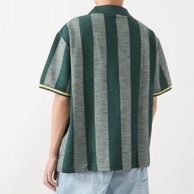 Model wearing Les Deux Stripe Football T-Shirt in pine green, back view showing bold vertical stripe jacquard pattern and short sleeves, styled with