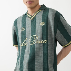 Model wearing Les Deux Stripe Football T-Shirt in pine green with vertical stripe jacquard pattern and yellow Les Deux logo script.