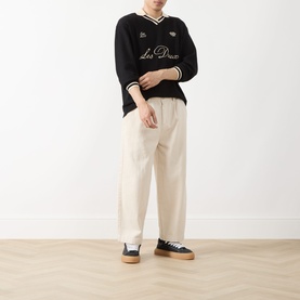Model wearing Les Deux Waffle Football Top in black with logo detail, styled with cream wide-leg trousers and black flatform trainers.