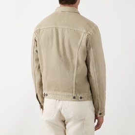 Model wearing Levis The Trucker Denim Jacket in yellow sand, rear view, styled with cream trousers. Button cuffs and adjustable hem visible.