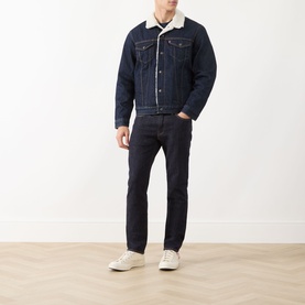 Model wearing Levi's Type III Sherpa Trucker Jacket in dark rinse denim with sherpa lining, styled with matching dark jeans and white trainers.