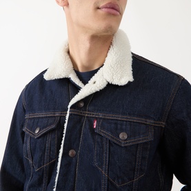 Model wearing Levi's Type III Sherpa Trucker Jacket in dark rinse denim with cream sherpa collar lining and branded button fastenings.