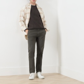 Model wearing Levis XX Mid-Rise Chino in Komodo Shady green, styled with a plaid overshirt, dark tee, and white trainers.
