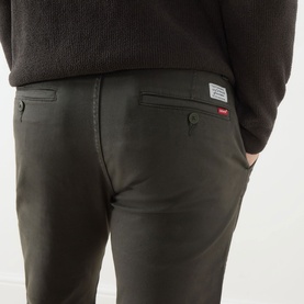 Model wearing Levi's XX Mid-Rise Chino in Komodo Shady green, showing rear logo patch, belt loops and stretch cotton fabric.