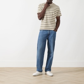 Model wearing Levis Stripe Logo T-Shirt in Martin Stripe Winter Pear, styled with blue straight-leg jeans and white trainers.