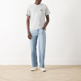 Model wearing a grey graphic T-shirt and light blue straight-leg jeans, styled with white trainers