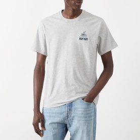 Model wearing grey marl crew neck T-shirt with small navy chest graphic, styled with light wash jeans
