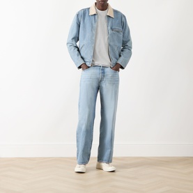 Model wearing light blue denim jacket with cream shearling collar, styled with matching light blue jeans and white trainers