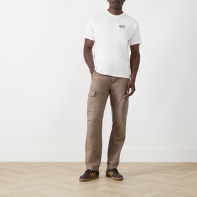 Model wearing Levis Music City Egret crew neck T-shirt with tan cargo trousers and brown striped trainers.