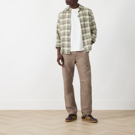 Model wearing Levis Music City Egret Crew Neck T in white, styled with green plaid overshirt, taupe cargo trousers and yellow-sole trainers.