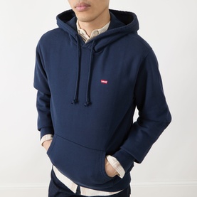 Model wearing Levis navy hoodie with small red logo chest badge, kangaroo pocket and drawstring hood, styled with a check shirt