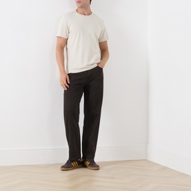 Model wearing Levi's 568 Loose Straight Jeans in Mudslides dark wash, styled with a cream T-shirt and brown trainers.