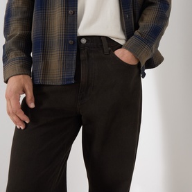 Model wearing Levi's 568 Loose Straight Leg Jeans in Mudslides OD dark wash, styled with a plaid shirt and white tee.