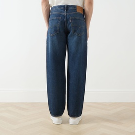 Model wearing Levi's 3049 Loose Jeans in Hard Rain dark blue wash, shown from behind with white trainers