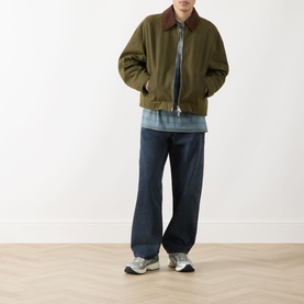 Model wearing Levis 578 Baggy Straight Leg Jeans in Time Forest dark indigo, styled with an olive bomber jacket and grey trainers.