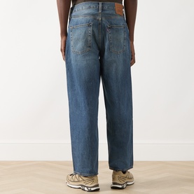 Model wearing Levi's 3049 Loose Jeans in Varnished Tarnish mid-blue wash, rear view, styled with beige chunky trainers.