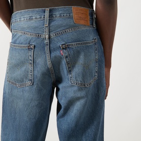 Model wearing Levi's 3049 Loose Jeans in Varnished Tarnish, close-up of back pockets with leather logo patch, mid-blue wash denim