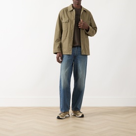 Model wearing Levi's 3049 Loose Jeans in Varnished Tarnish mid-blue wash, styled with a khaki overshirt and grey trainers.