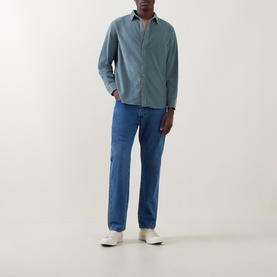 Model wearing Levis Reg Shirt in Stormy Sea blue cotton, styled with mid-blue jeans and white trainers