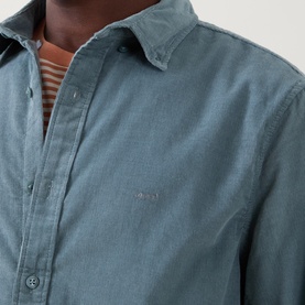 Model wearing Levi's Reg Shirt in Stormy Sea cotton, styled over a striped crew-neck top, close-up of chest and collar detail.