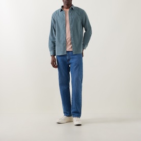 Model wearing Levi's Stormy Sea Reg Shirt in blue cotton, styled with mid-blue jeans, pink tee and white trainers.