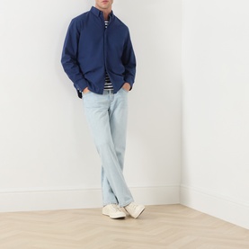 Model wearing Levi's Medieval Blue Garment Dye Reg Shirt, styled with a striped tee, light wash jeans, and white trainers.