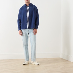 Model wearing Levi's Medieval Blue Garment Dye Reg Shirt, styled with a stripe tee, light wash jeans and white trainers.