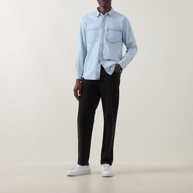 Model wearing Levi's light wash cotton reg shirt with chest pockets, styled with black trousers and white trainers.