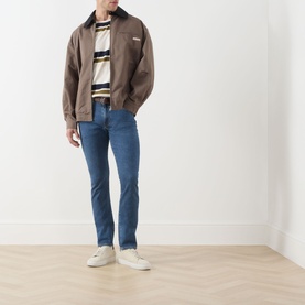 Model wearing Levi's 3049 Slim Jeans in Laugh It Off blue, styled with a brown zip jacket, striped top and white trainers.