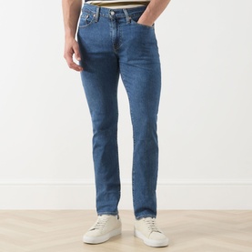 Model wearing Levis 3049 Slim Jeans in Laugh It Off mid blue wash, styled with white leather trainers.