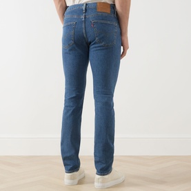 Model wearing Levi's 511 Slim Jeans in Laugh It Off mid-blue wash, rear view showing classic five-pocket styling and leather patch detail.