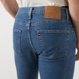 Model wearing Levi's 3049 Slim Jeans in Laugh It Off mid-blue wash, rear view showing leather patch and red tab detail.