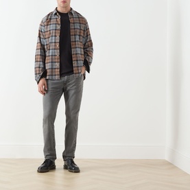 Model wearing Levis 3049 Slim Jeans in Granite Shadow, styled with a brown plaid overshirt, black tee and black leather shoes.