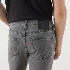 Model wearing Levi's 3049 Slim Jeans in Granite Shadow grey denim, rear view showing signature red tab and back pockets.