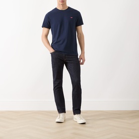 Model wearing Levi's 511&trade; Slim Leg Jeans in dark blue with slim fit, paired with a navy T-shirt and white trainers.