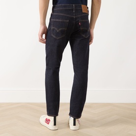 Model wearing Levi's 511 Slim Leg Jeans in dark blue, rear view showing arcuate stitching and logo patch, styled with white trainers