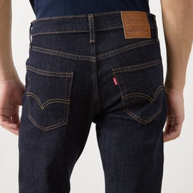 Model wearing Levi's 511 Slim Leg Jeans in dark blue, showing rear view with arcuate stitching, logo patch, and red tab detail.