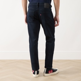 Model wearing Levi's 511&trade; Slim Leg Jeans in Why So Blue dark wash, rear view, styled with black and white high-top trainers.